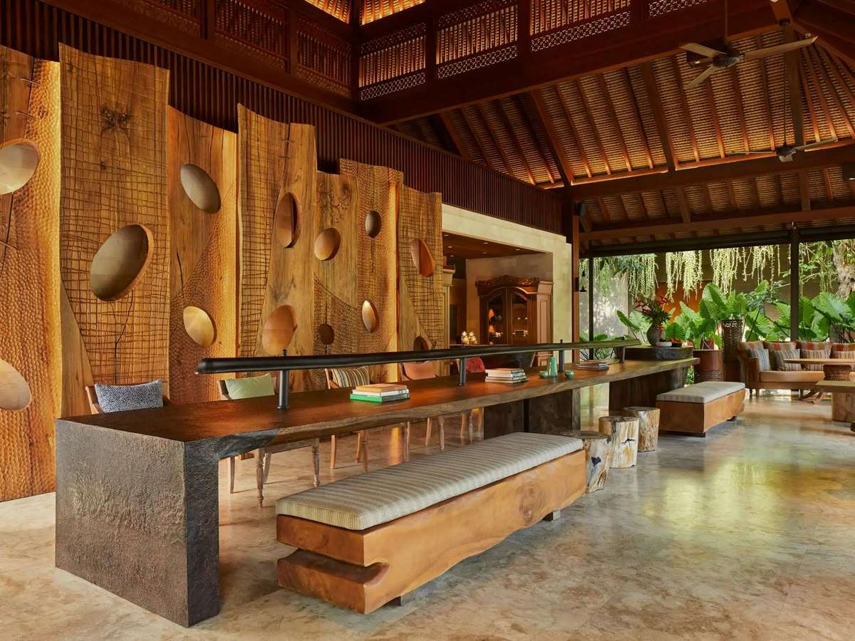 Lobby communal table with sculptural wood wall and Joglo roof.