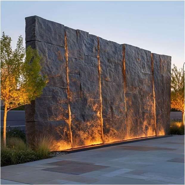 Dramatic stone wall with uplighting and textured foliage.